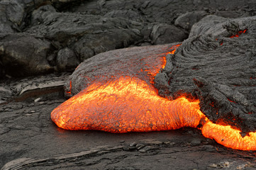 Detailed view of an active lava flow, hot magma emerges from a crack in the earth, the glowing lava...