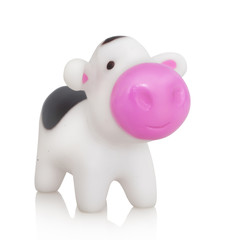 Little smiling moo-cow plastic toy. Isolated on white background with shadow reflection. With clipping path. Lovely cow on white bg. With vector path. Heifer plaything on reflective underlay.