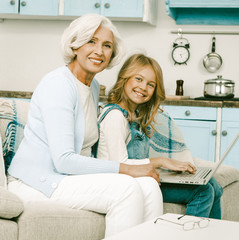 Grandmother happy to help her granddaughter with laptop