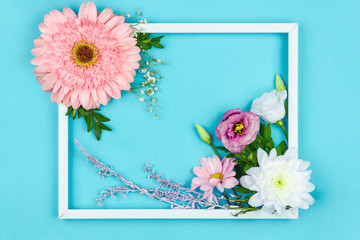 Composition of pink and white flowers are lined inside frame on blue background. Greeting card template, invitation for celebration, party. Happy mothers, women day, spring, easter concept.