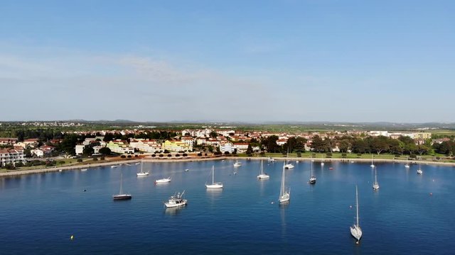 AERIAL: Flying into the a little harbor. Sail boats are laying still in the blue water. Umag, Croatia