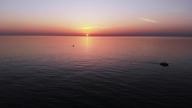 AERIAL: Amazing sunset over the sea of Umag, Croatia. Orange and purple colors. Little boats in the water.