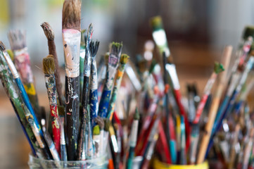 Fototapeta premium A lot dirty artist paint brushes in a bucket