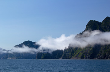 Clouds sitting on cliffs along Kenai Fjords in Alaska