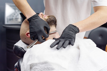 beard modeling in Barber shop, beard care for men, male beauty and care concept, shaving with a straight razor
