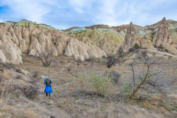Obraz premium Hiker is walking down the valley with spectacular rock formations on the background. Activities in Cappadocia,Turkey.