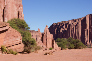 Red mountains in the desert with stone rock formations trees and green blue sky
