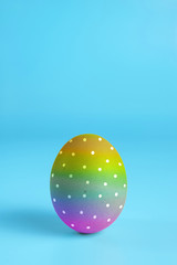 One bright rainbow painted easter egg on blue surface. Colorful easter eggs decoration. Copy space for text.