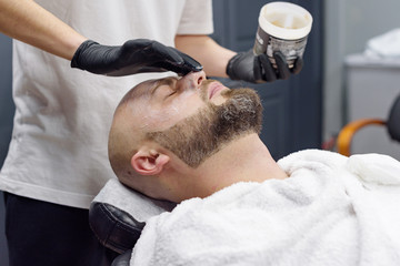 Obraz na płótnie Canvas beard modeling in Barber shop, beard care for men, male beauty and care concept, applying the scrub to the face