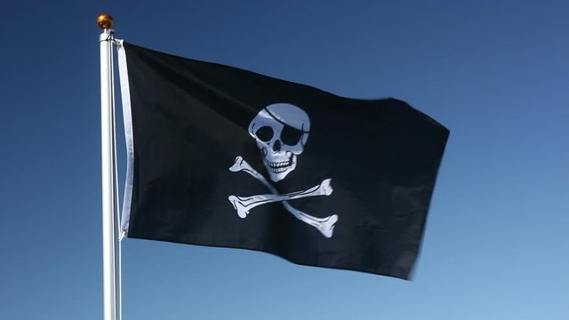 Pirate Flag flying in the wind outside with Blue sky Behind - Skull and Crossbones flag - Stock Video Clip Footage