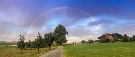 Pretty rainbow during sunrise in a coutnryside of switerland. Emmental, Canton bern