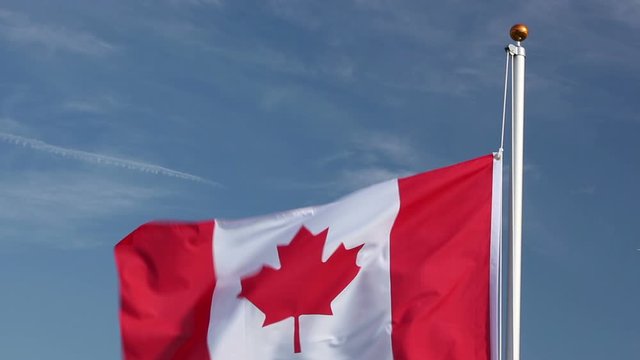 Raising The Canada Flag, Flying  In The Wind Outside With Blue Sky Behind - Canadian Flag Stock Video Clip Footage