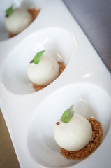 White chocolate balls pralines on crisp on white circular dish with mint on the top