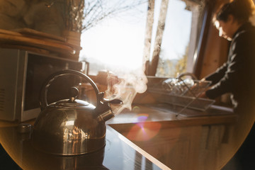 Tea kettle with boiling water; steam against a black background.