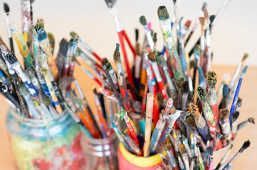 Fototapeta premium A lot dirty artist paint brushes in a bucket