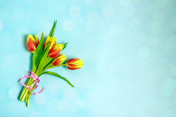 Spring background with tulips. Bouquet of yellow and red tulips on a blue background, top view, bokeh effect Congratulatory background, birthday, mother's day, women's day, congratulatory background 