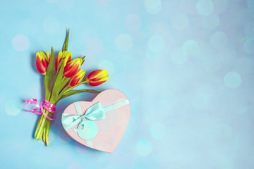 International Women's Day concept.Bouquet of tulips and a box with a gift on a blue background. Flat lay, cop concept.Bouquet of tulips and a box with a gift on a blue background. Flat lay, copy space