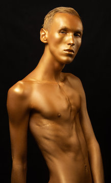 Naked men gold Man in gold paint. Guy fashion model beauty. Shiny body art paint gold on a black background. shot. portrait