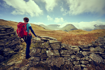 A female hiker taking in the mountain views of Hayeswater, the summits of Gray Crag, Thornthwaite and a cloud covered Stony Cove Pike in the distance. Lake District UK.