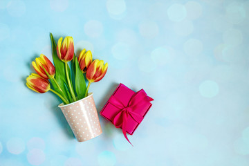 International Women's Day concept.Bouquet of tulips and a box with a gift on a blue background. Flat lay, copy space