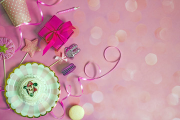 Holiday accessories, disposable tableware, gift box, pasta, ribbons on a pink background, bokeh effect, top view, copy space