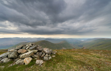 Dark clouds gather over the mountains in the evening from the summit of Rampsgill Head with Rest Dodd, The Nab and Martindale Common in the distance with Ramps Gill Far below in the Lake District.