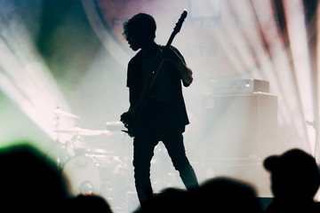 Double exposure of festival crowd with magical lights and silhouette of a guitarist.