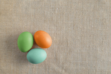 Top view of three bright painted easter eggs on canvas surface. Colorful easter eggs decoration. Flat lay, top view. with copy space for text.
