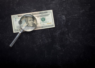 Andrew Jackson through the magnifying glass on the twenty dollar bill on a black slate background...