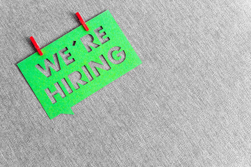 "We're hiring" green banner on grey texture background with space for text. Job vacant and employment concept.