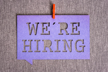 "We're hiring" purple banner on grey texture background. Job vacant and employment concept.