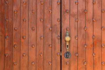 Historical wooden door with ornate doorknob. Front View.