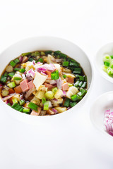 Traditional Russian summer cold soup okroshka with kvass in bowl on white background.
