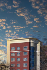 A red brick office building with many windows under a blue sky