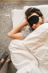 man sleeping in bed in a sleep mask