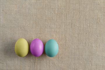 Top view of three bright painted easter eggs on canvas surface. Colorful easter eggs decoration. Flat lay, top view. with copy space for text.