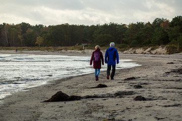 Man and woman walking on sandy beach a autumn day