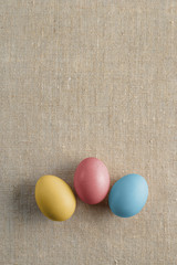 Top view of three bright painted easter eggs on canvas surface. Colorful easter eggs decoration. Flat lay, top view. with copy space for text.