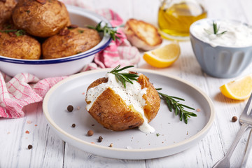 Whole potato roasted with rosemary and spices, served with sour cream sauce. Vegetarian dish. 