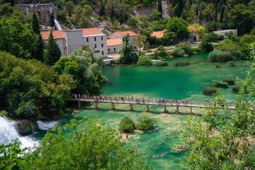 Fototapeta na wymiar View of waterfall and wooden bridge across the river in Krka National Park, Croatia