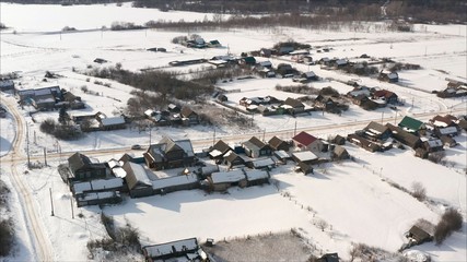 Russian village in winter shot from a quadrocopter. Aerial view of the typical Russian village covered with snow and countryside road. Shot. Winter in Russia, the periphery of Russia.