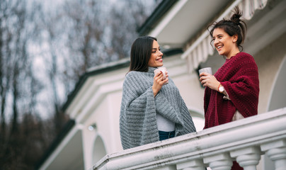 Naklejka premium Two beautiful young women enjoying together on terrace at their country house.