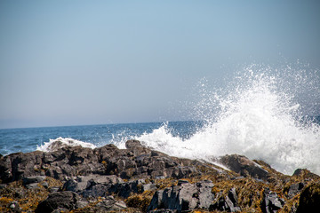 Fototapeta na wymiar Wave crashing up against the rocks at the ocean