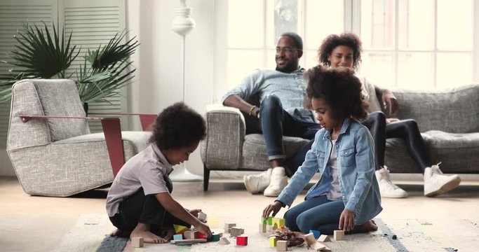 African kids playing on floor while parents relaxing on sofa