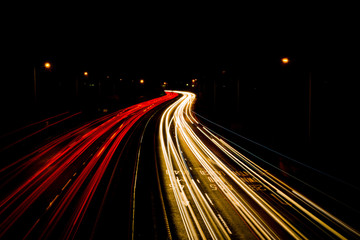 Light trails from moving car headlights and rear vehicle lights creating moving blurred motion at...