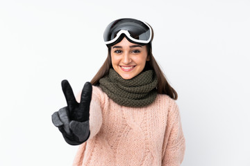 Skier girl with snowboarding glasses over isolated white wall smiling and showing victory sign