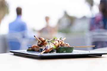 Sticks of salty grilled squids served in a dark board