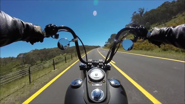 First person pov shot of professional biker riding fast downhill highway road on black motor bike in amazing landscape