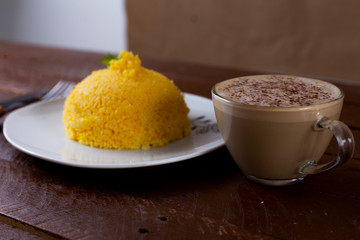 Cuscuz with cheese, typical northeastern food on a white plate and wooden background and coffee