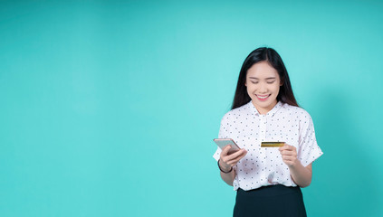 credit card career e-commerce trading Technology, Online shopping, Digital banking smartphone,Smiling Asian woman using credit card business payment on a blue isolated background for banner website